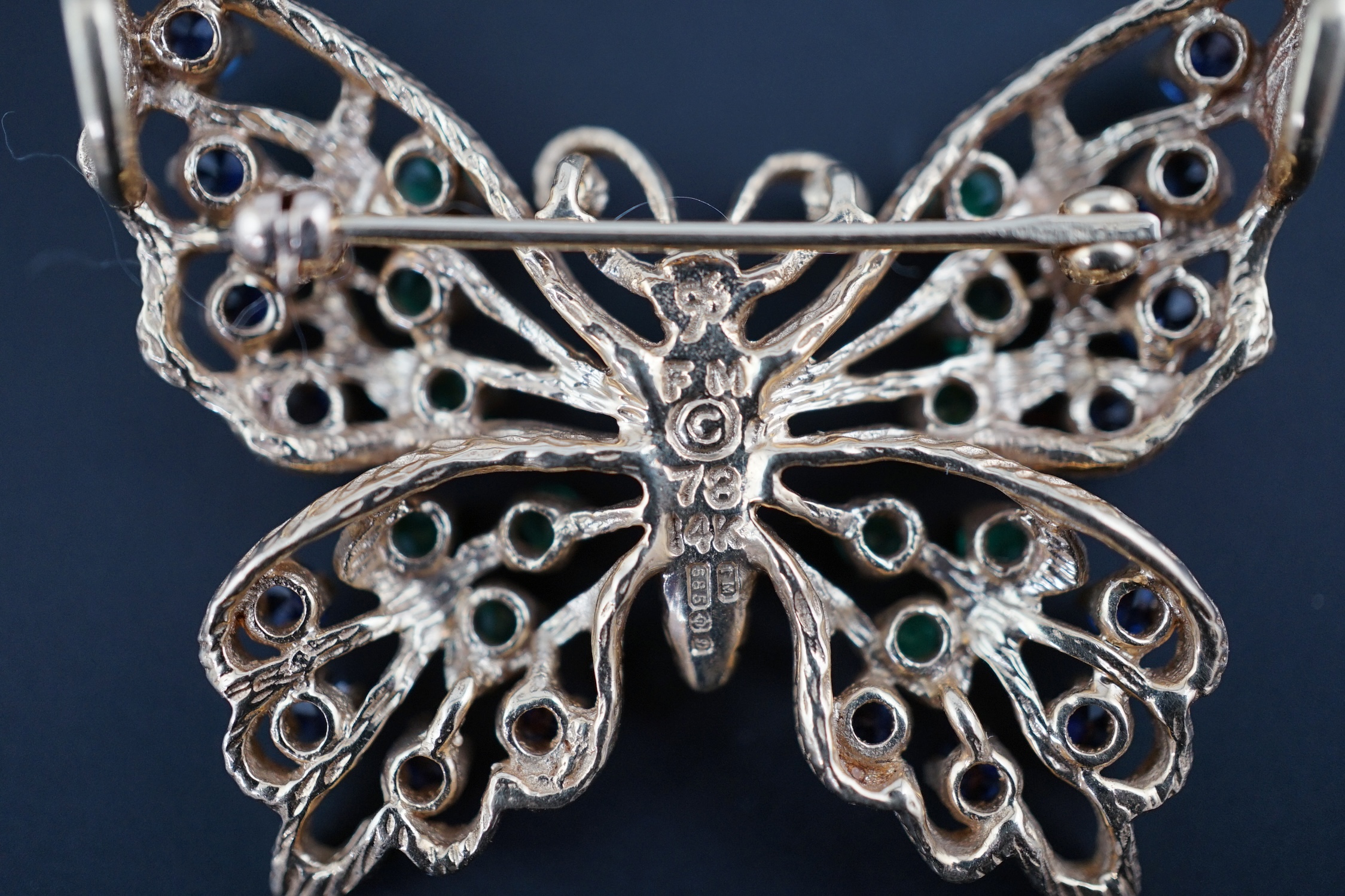 A modern pierced 14ct gold, emerald and sapphire cluster set butterfly brooch